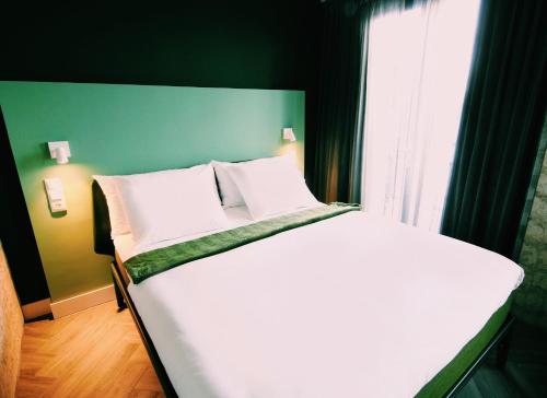 a bedroom with a white bed with a green wall at Bed, Bites & Business Hotel Rotterdam in Rotterdam