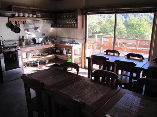 a kitchen with tables and chairs and a large window at Refugio Ecobox Andino in Las Trancas