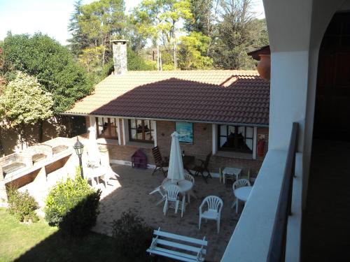 a house with a patio with chairs and an umbrella at Posada San Bras in Villa General Belgrano