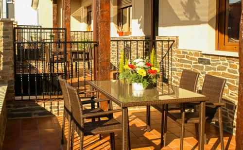 ein Tisch mit einer Vase mit Blumen auf einem Balkon in der Unterkunft Apartamentos Rurales El Calama in Zarza de Granadilla