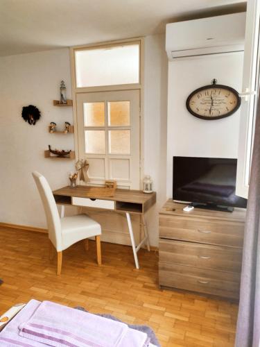 a living room with a desk and a clock on the wall at Apartament Bogoslovovi in Varna City