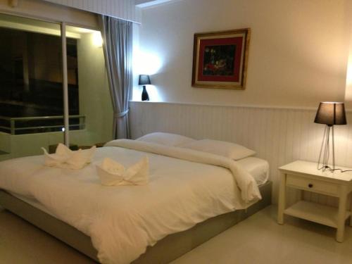 a bedroom with a bed with white sheets and a window at Cha_Inn @ Cha Am in Cha Am