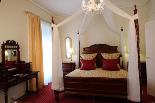 a bedroom with a canopy bed with red pillows at Store Restrup Manor House in Store Restrup