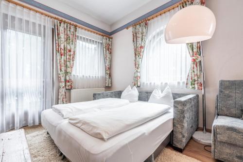 a bedroom with a white bed and a chair at Appartements Mair in Mayrhofen
