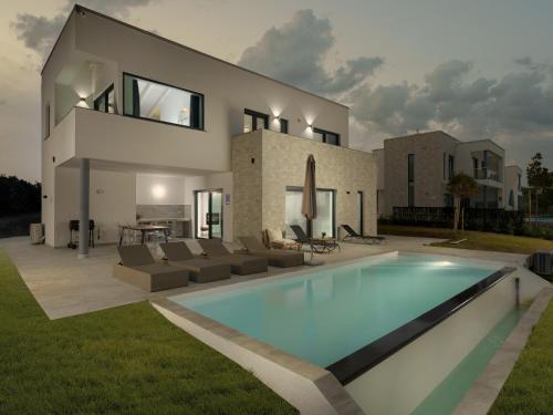 a villa with a swimming pool in front of a house at Sea View Villa Cala Royal in Krnica