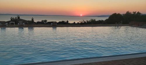 a large swimming pool with a sunset in the background at Casale sul Lago Trasimeno in San Feliciano