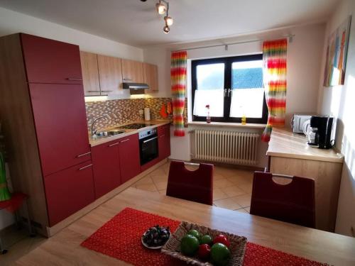 eine Küche mit roten Schränken sowie einem Tisch und Stühlen in der Unterkunft Ferien bei Fuchs in Stein