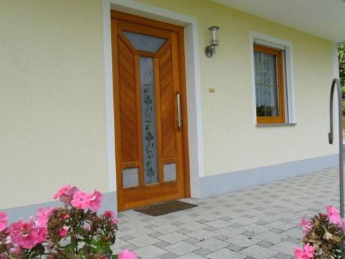 a wooden door of a house with pink flowers at Holiday flat with swimming pool in Prackenbach in Viechtach