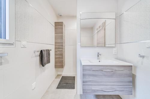 uma casa de banho branca com um lavatório e um espelho em Les Bambous em Sanchey