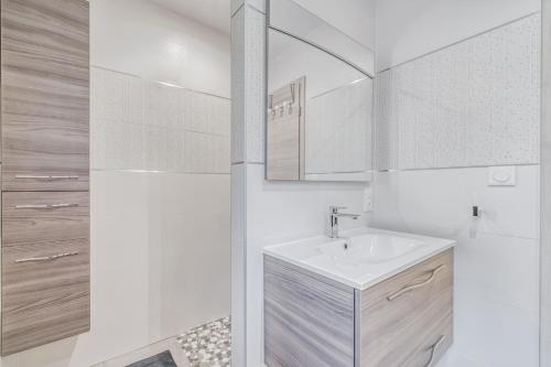 ein weißes Badezimmer mit einem Waschbecken und einem Spiegel in der Unterkunft Les Roseaux in Sanchey