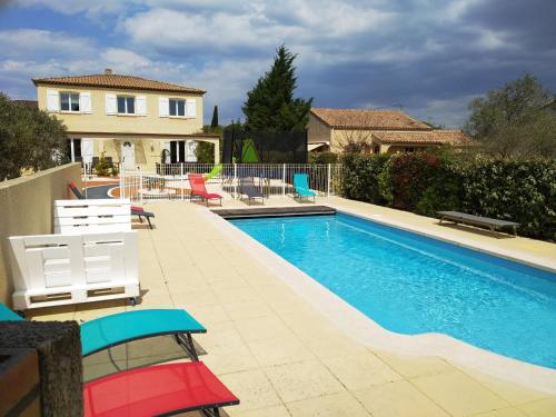 une piscine avec des chaises et une maison dans l'établissement villa classée 4 étoiles avec piscine et boulodrome, à Canet