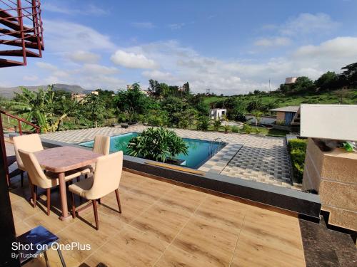 a patio with a table and chairs and a swimming pool at ROYAL MEADOWS IGATPURI 2BHK POOLSIDE VILLA in Igatpuri