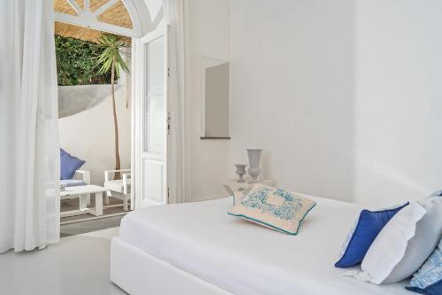 a white bedroom with a white bed and blue pillows at Villa La Pergola Capri in Capri