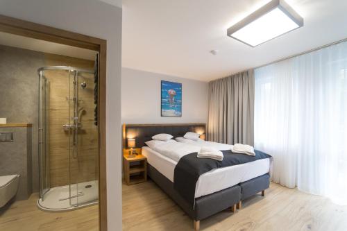 Habitación de hotel con cama y ducha en Villa Aura, en Świnoujście