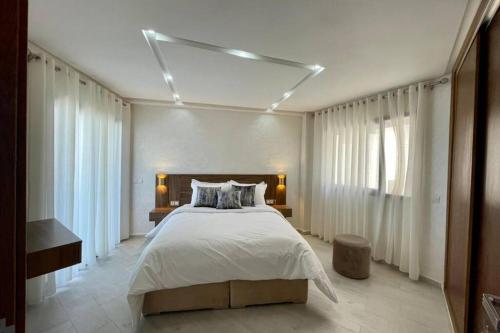 Un dormitorio con una cama grande con sábanas blancas. en Superbe appartement en front de mer haut standing, en Kenitra