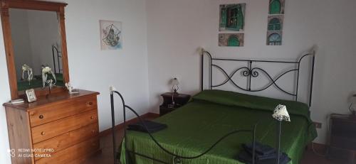 a bedroom with a green bed and a wooden dresser at House Italia Holiday in Trabia