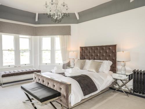 a white bedroom with a large bed and a chandelier at Telford House in Bangor