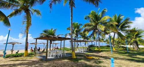a beach with palm trees and a table and chairs at Hotel Brisa dos Abrolhos in Alcobaça