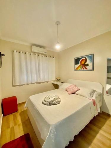 a bedroom with a white bed and a red chair at Pousada Quedas D'água in Foz do Iguaçu