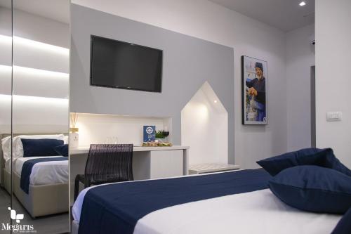 a bedroom with two beds and a tv on the wall at Megaris Luxury Suite Rooms in Naples