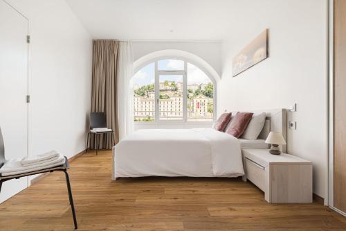 a white bedroom with a bed and an arched window at Design et charme, 100m2 face à la Saône in Lyon