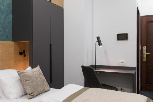 a bedroom with a bed with a desk and a chair at Garni Hotel Cirman in Ljubljana