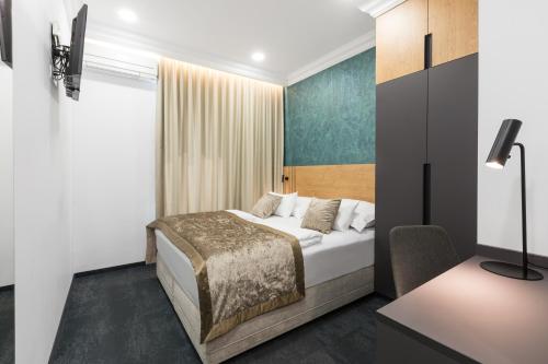 a bedroom with a bed and a desk and a tv at Garni Hotel Cirman in Ljubljana