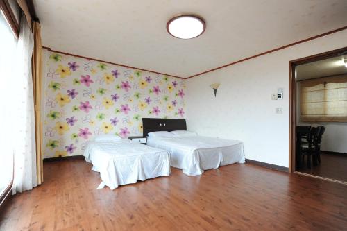 two beds in a room with flowers on the wall at Jeju Feel House in Jeju