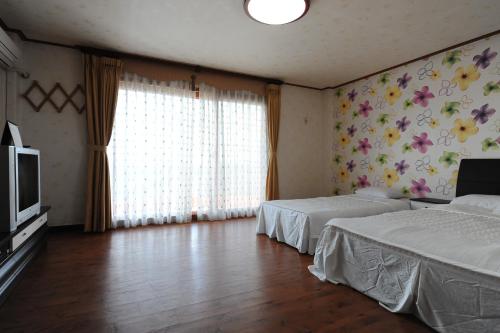 a bedroom with two beds and a tv and curtains at Jeju Feel House in Jeju