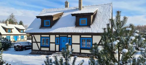 a house with blue doors in the snow at Kaszuby, dom kaszubski nad jeziorem Danielowa Dolina in Szymbark