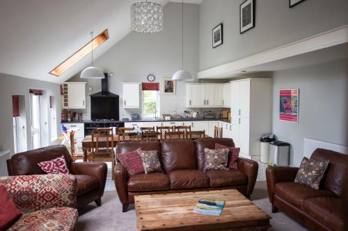 a living room with couches and a table and a kitchen at Wellstone Cottages - Honey Coach House in Pembrokeshire