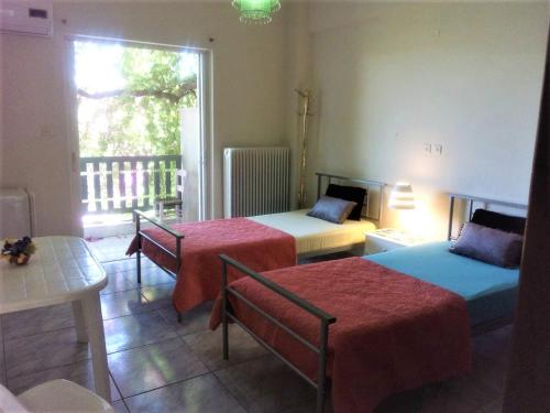 a room with two beds and a table and a window at Vacations in Patra Rooms in Patra