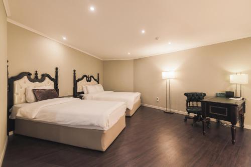 a hotel room with two beds and a desk and a desk at Aria Hotel in Seogwipo