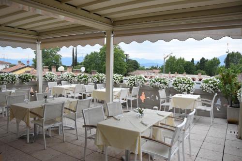 un restaurante con mesas blancas y sillas en la azotea en Aparthotel All'Orologio, en Peschiera del Garda