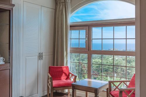 a room with two chairs and a table and a large window at Aria Hotel in Seogwipo