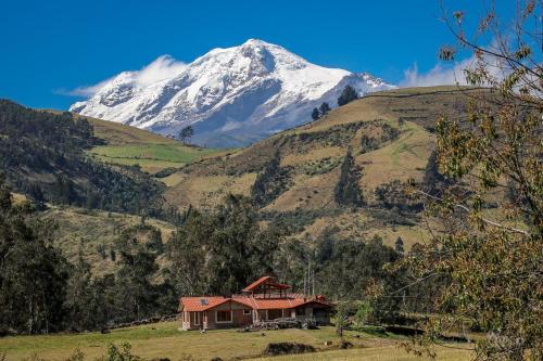 a house in front of a snow covered mountain at Santa Rosa de Lima Hostal Zuleta in Zuleta