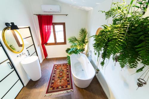 La salle de bains est pourvue d'une baignoire blanche et de plantes. dans l'établissement Flor de Mandarina, à Sa Pobla