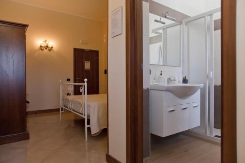 ein Bad mit einem Waschbecken und ein Bett in einem Zimmer in der Unterkunft Kalinifta Residence in Carpignano Salentino