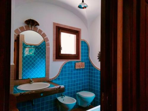 a blue tiled bathroom with a sink and a toilet at Casa Rustica in Dorgali