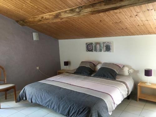 a bedroom with a large bed with a wooden ceiling at La Frouardière, 3 gîtes de charme in Antigny