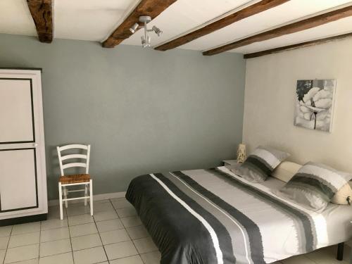 a bedroom with a bed and a chair in it at La Frouardière, 3 gîtes de charme in Antigny