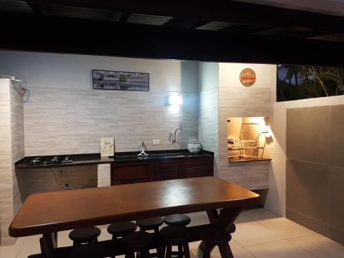 a kitchen with a wooden table and some bar stools at Casa- Maresias 3 minutos da praia in Maresias