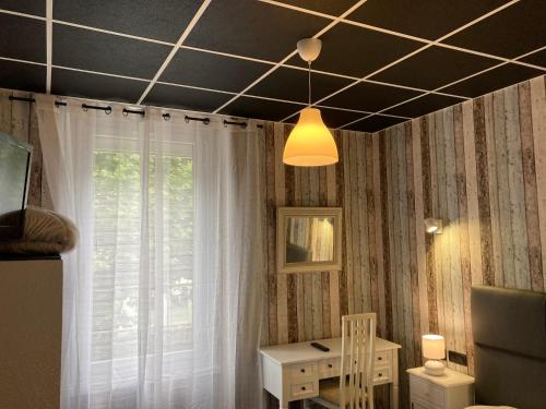 Cette chambre dispose d'un plafond avec une table et une fenêtre. dans l'établissement Hôtel Le Faisan, à Montluçon