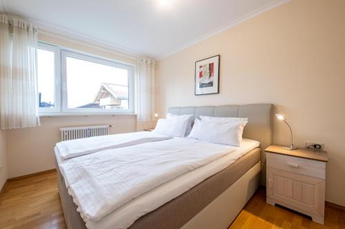 een slaapkamer met een groot wit bed en een raam bij Amici in Garmisch-Partenkirchen