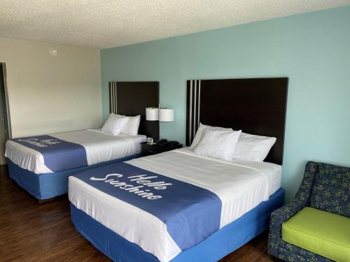 two beds in a hotel room with a chair at Days Inn by Wyndham Goldsboro in Goldsboro