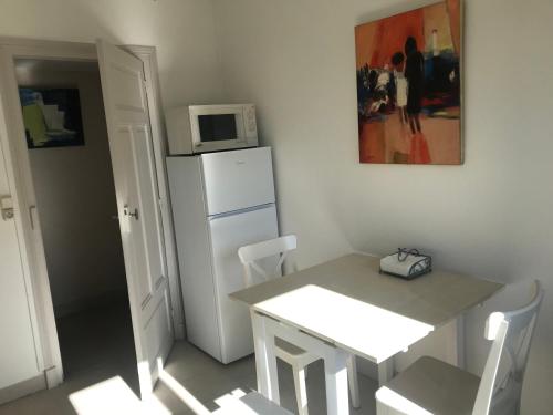 - une cuisine avec une table et un four micro-ondes au-dessus d'un réfrigérateur dans l'établissement Appartement Marion en coeur de ville 2 à 4 personnes, à Bort-les-Orgues