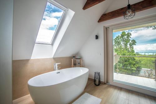 a white bath tub in a bathroom with a large window at Csipetnyi Csoda Vendégház in Felsőörs