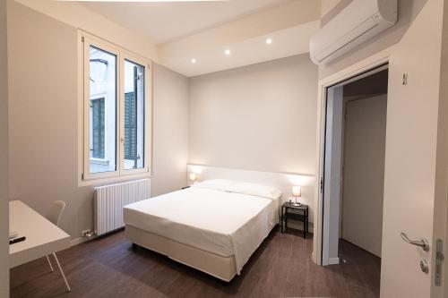 una camera da letto con un letto bianco e una finestra di Good night Romeo - Eleganti Dimore a Verona