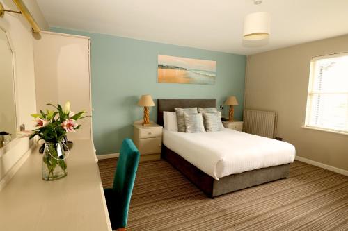 a bedroom with a bed and a table with a vase of flowers at Causeway Hotel in Bushmills