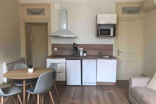 une petite cuisine avec une table et des chaises et une cuisine avec un canapé dans l'établissement BeauneAppart - Centre- Climatisation - Parking gratuit, à Beaune